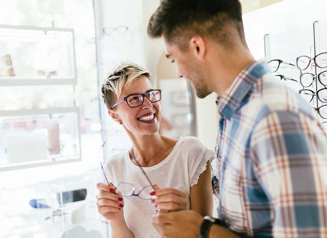 Individual Vision Insurance - Smiling Young Couple after an Eye Exam and Trying on Glasses before Making a Purchase