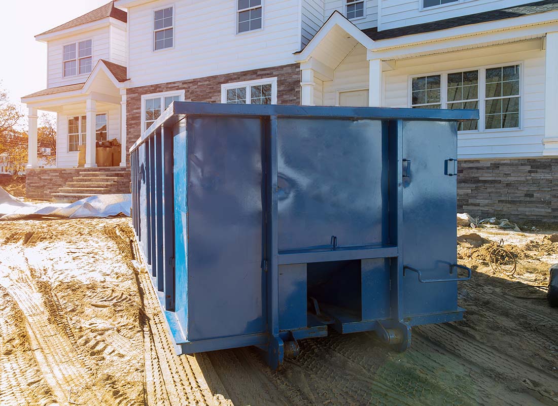Roll-off Contractor Insurance - Blue Dumpster in Front of a New Home for Waste and Construction Materials at a Construction Site